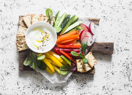 80598146-healthy-snack-raw-vegetables-and-yogurt-sauce-on-a-wooden-cutting-board-on-a-light-background-top-vi