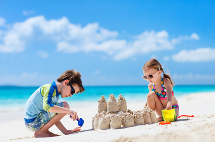 Brother and sister making sand castle at tropical beach
