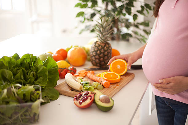 Cropped view of pregnant woman making a healthy drink using fruits and vegetable.